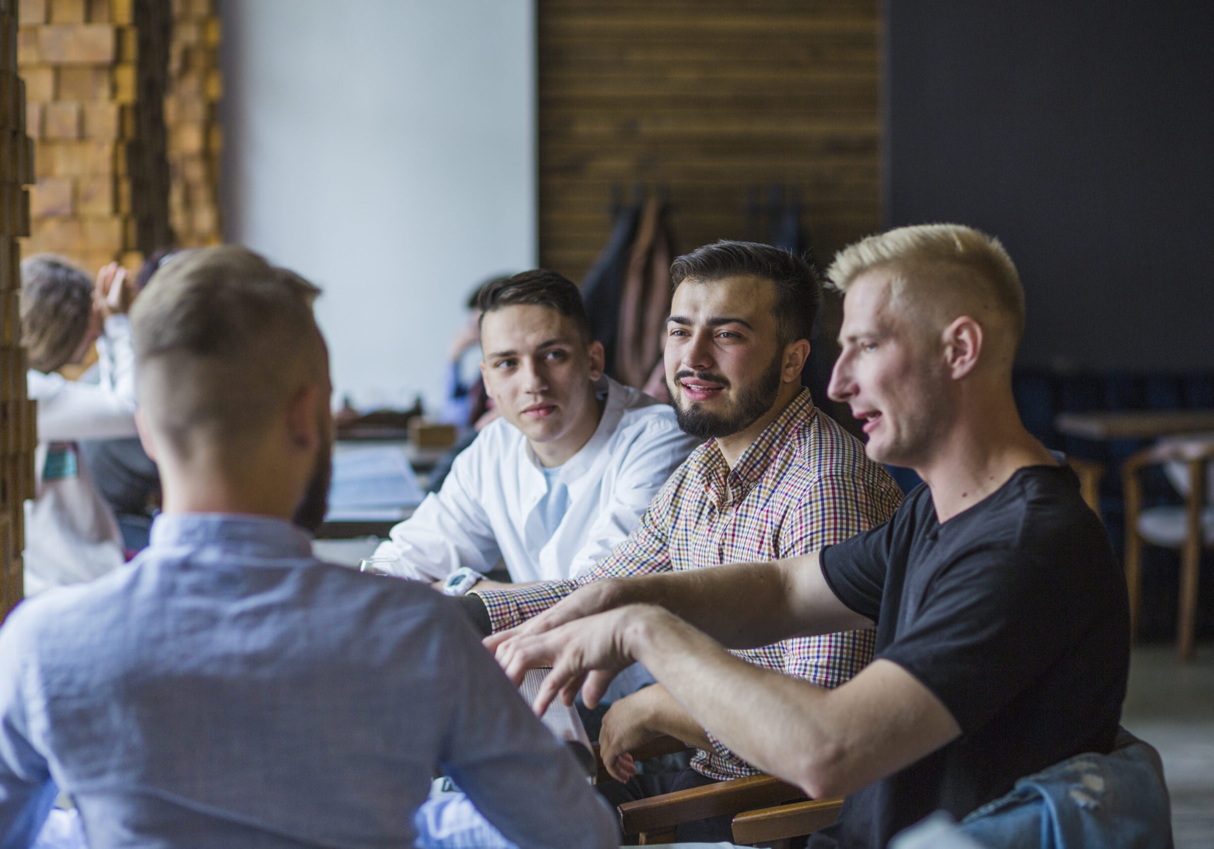 young-man-sitting-restaurant-explaining-strategy-his-friends